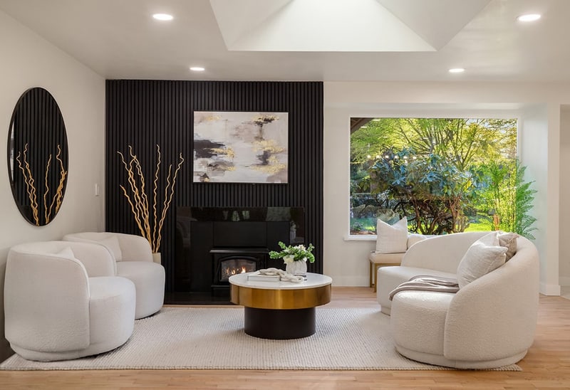 Living room with a gas fireplace set into a dark slatted wall, two curved bouclé chairs, and a wide window onto the garden.