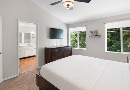 Primary bedroom with adjoining bathroom and tree-lined views.