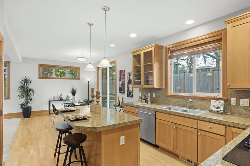Kitchen with maple cabinetry, granite counters, a breakfast island with stools, and a window above the sink.